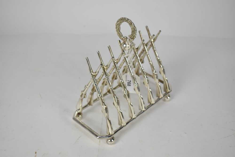 Lot 768 - Impressive early 20th century novelty silver plated six division toast rack in the form of crossed guns, with central laurel leaf wreath, marked Superior S.P. Co, 19.5cm in length.