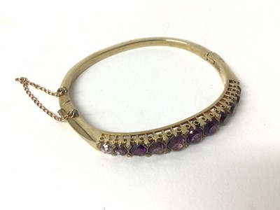 Lot 212 - Victorian style gold and amethyst hinged bangle with graduated round mixed cut amethysts and diamond accents to the claws with pierced gallery.