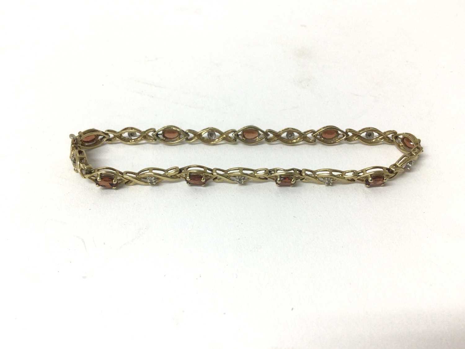 Lot 214 - Garnet and diamond bracelet with a line of oval cut garnets and single cut diamonds in 9ct gold setting, 18.5cm length.