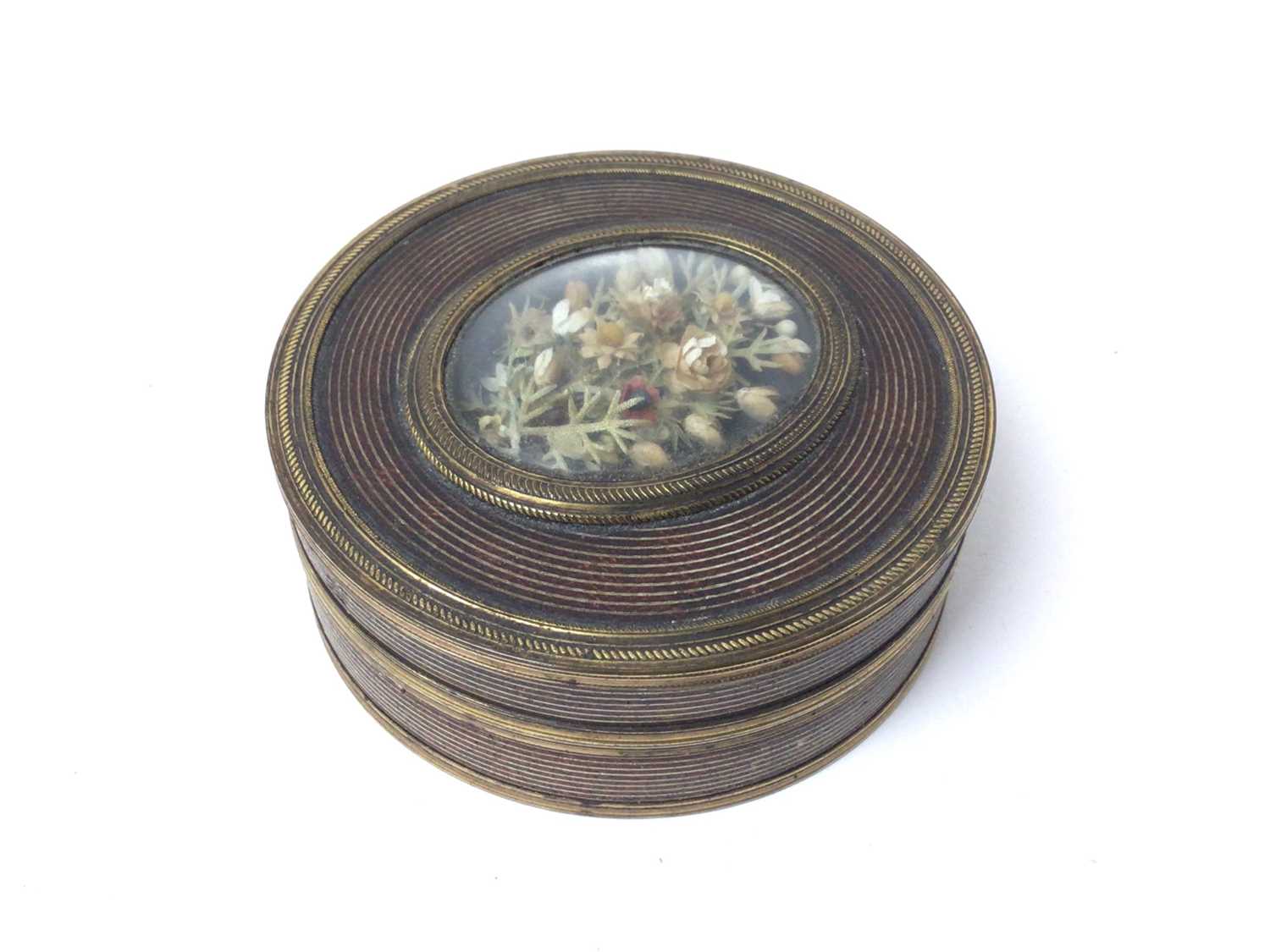 Lot 210 - Unusual Georgian red tortoishell, red lacquer and gilt metal mounted circular snuff box with cut paper floral display under double sided domed glass 7.6 cm diameter