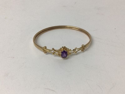 Lot 216 - 9ct gold and amethyst bangle with an oval mixed cut amethyst and gold scroll shoulders.