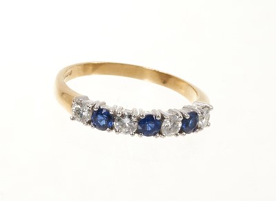 Lot 513 - Sapphire and diamond eternity ring with a half hoop of four round brilliant cut diamonds interspaced by three round mixed cut blue sapphires in claw setting on 18ct yellow gold shank. Estimated tot...