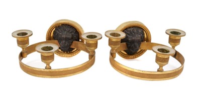 Lot 742 - Pair of Empire bronze and ormolu three light wall appliqués, with lion mask boss wall mount supporting tooled projecting ring with three sconces, 19cm wide