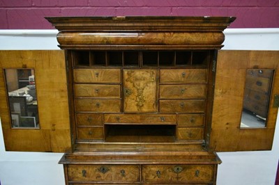 Lot 1404 - Early 18th century walnut veneered secretaire chest on chest, the top with frieze drawer, fitted interior with pigeon holes and drawers enclosed by two doors, the base with two short and two long d...