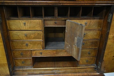 Lot 1404 - Early 18th century walnut veneered secretaire chest on chest, the top with frieze drawer, fitted interior with pigeon holes and drawers enclosed by two doors, the base with two short and two long d...