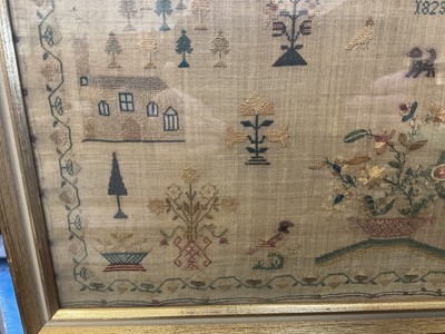 Lot 792 - George IV needlework sampler, by Elizabeth Sandland Aged 14, 1823. A prayer above houses and trees with birds, dog and a large central pot of flowers, all within an acorn border. Gilt frame