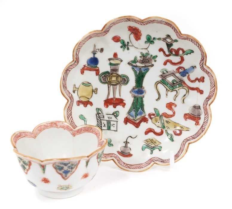 Lot 18 - A Chinese famille verte tea bowl and saucer, Kangxi period, decorated with precious objects and auspicious symbols, marked to bases