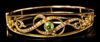 Lot 427 - Edwardian peridot and seed pearl hinged bangle,...