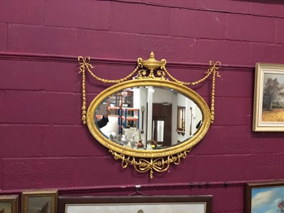 Lot 1059 - Edwardian Adam-style gilt framed wall mirror with bevelled oval plate, urn, swag and ribbon mounts 94 cm high, 100 cm wide