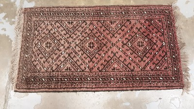 Lot 1181 - Eastern prayer mat with geometric decoration on red ground, 94cm x 53cm