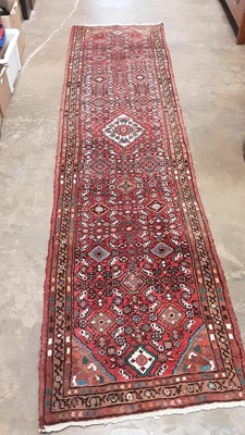 Lot 1216 - Eastern runner with geometric decoration on red ground, 305cm x 76cm