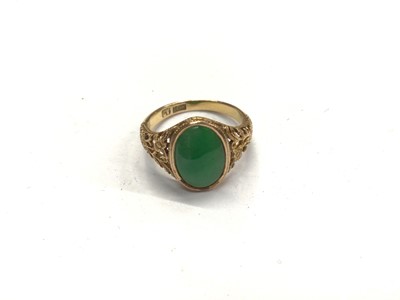 Lot 875 - 18ct gold green hard stone oval panel ring with carved floral scroll shoulders, size M