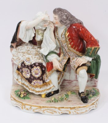 Lot 5 - A large 19th century continental porcelain group showing a couple seated on a bench, the gentleman helping to remove something from the lady's eye, 25cm high x 24cm wide