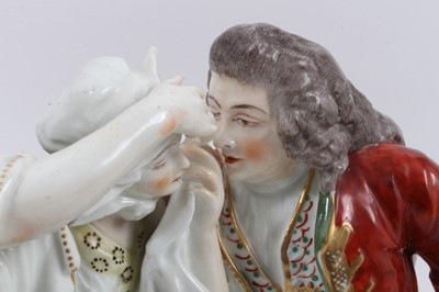 Lot 5 - A large 19th century continental porcelain group showing a couple seated on a bench, the gentleman helping to remove something from the lady's eye, 25cm high x 24cm wide