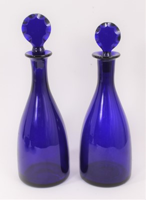 Lot 73 - A near pair of 19th century Bristol blue glass decanters with facet-cut stoppers, the larger measuring 32cm high, together with a near pair of Bristol blue finger bowls (4)