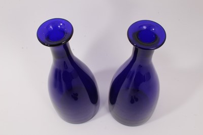 Lot 73 - A near pair of 19th century Bristol blue glass decanters with facet-cut stoppers, the larger measuring 32cm high, together with a near pair of Bristol blue finger bowls (4)