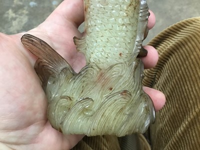 Lot 790 - Chinese russet jade carving of a pike in waves, 20cm high, together with carved jade snuff bottle and stopper and a carving of a fruit. (3)