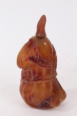 Lot 790 - Chinese russet jade carving of a pike in waves, 20cm high, together with carved jade snuff bottle and stopper and a carving of a fruit. (3)