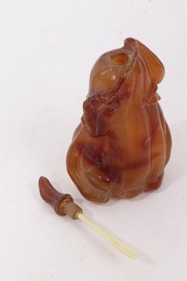 Lot 790 - Chinese russet jade carving of a pike in waves, 20cm high, together with carved jade snuff bottle and stopper and a carving of a fruit. (3)