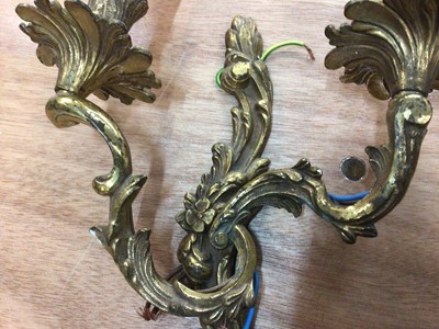 Lot 59 - A pair of gilt metal two-branch wall lights of scrolling acanthus form, 45cm high including bulbs