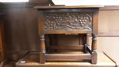 Lot 1062 - Carved oak box stool with hinged lid on turned and block legs joined by stretchers, together with an oak oval folding occasional table (2)