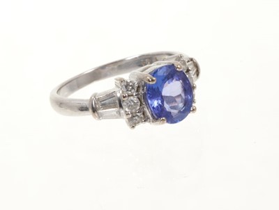 Lot 454 - Tanzanite and diamond ring with an oval mixed cut tanzanite flanked by six round brilliant cut diamonds and tapered baguette cut diamond shoulders on 18ct white gold shank.