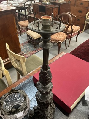 Lot 1453 - Pair of 19th century bronze candlesticks converted for electricity, each with inverted cut glass bowls, raised on flared column with mask swag and stiff leaf ornament, 71cm