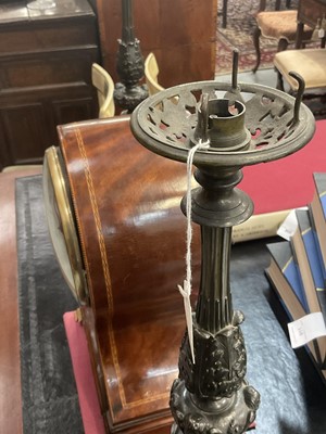 Lot 1453 - Pair of 19th century bronze candlesticks converted for electricity, each with inverted cut glass bowls, raised on flared column with mask swag and stiff leaf ornament, 71cm