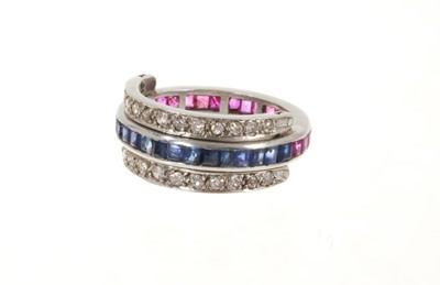 Lot 521 - A ruby, sapphire and diamond eternity swivel ring, the main band channel set with calibré cut blue sapphires on one side and calibré cut rubies to the other, between eight-cut diamond set hinged ba...