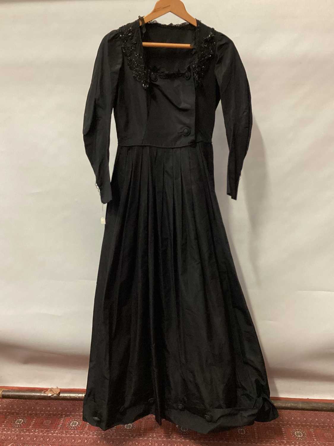 Lot 2065 - Victorian black dress with flat front opening, pleated skirt with buttoned hem and leg of mutton sleeve.  Plus a long black evening jacket, black applique silk edged in chain stitch on black net la...