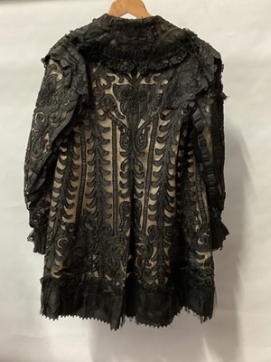 Lot 2065 - Victorian black dress with flat front opening, pleated skirt with buttoned hem and leg of mutton sleeve.  Plus a long black evening jacket, black applique silk edged in chain stitch on black net la...