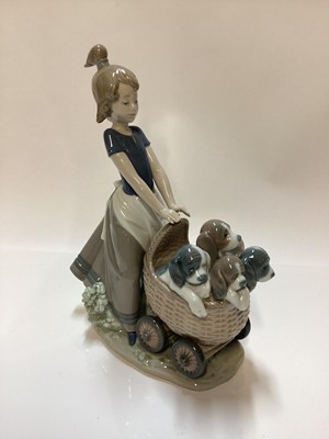 Lot 1185 - Three Lladro porcelain figure groups - girl with pram full of puppies 5364, girl with dog 5688 and girl on tricycle with kitten 5679
