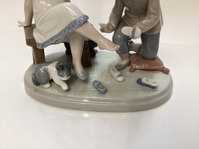 Lot 1187 - Four Lladro porcelain figures - clown with violin 5472, young couple 5555, boy and girl trying on shoes 5361 and girl with basket of puppies