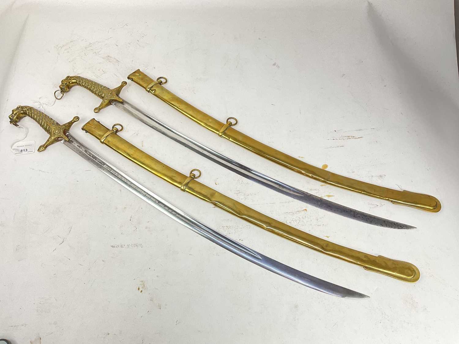 Lot 813 - Pair Regency military musicians' swords with cast leopard head and shell hilts, plain curved blades in brass scabbards (both stuck in their scabbards due to dents)