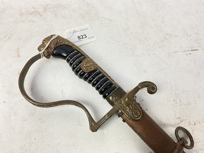 Lot 823 - Nazi Cavalry Officer's sword with brass lions head pommel and glass eyes, stirrup hilt with eagle and swastika langet, plain fullered blade in scabbard