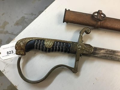 Lot 823 - Nazi Cavalry Officer's sword with brass lions head pommel and glass eyes, stirrup hilt with eagle and swastika langet, plain fullered blade in scabbard