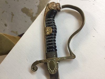 Lot 823 - Nazi Cavalry Officer's sword with brass lions head pommel and glass eyes, stirrup hilt with eagle and swastika langet, plain fullered blade in scabbard