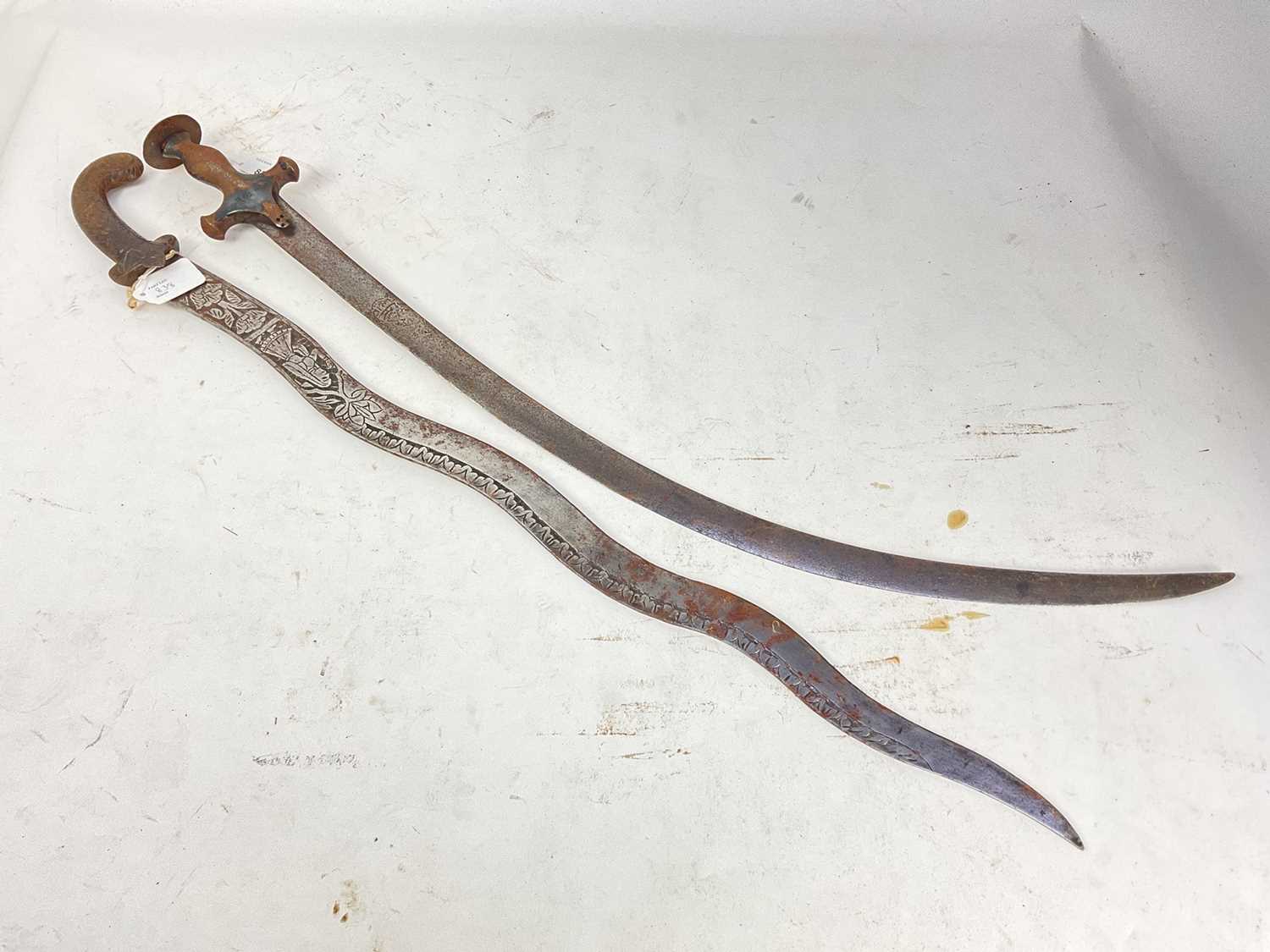 Lot 838 - 19th century Indian Tulwar with steel hilt and curved blade and old Indian dagger with waved blade decorated with figures and flowers (2)