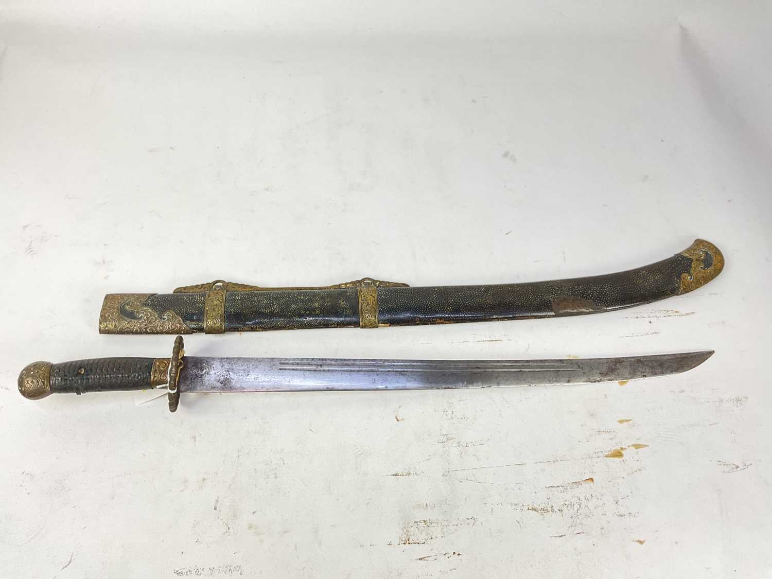 Lot 839 - Late 19th century Chinese military sword with brass mounts with scroll work arabesques, leather bound grip, slightly curved fullered blade in brass mounted shagreen covered scabbard, 80cm overall