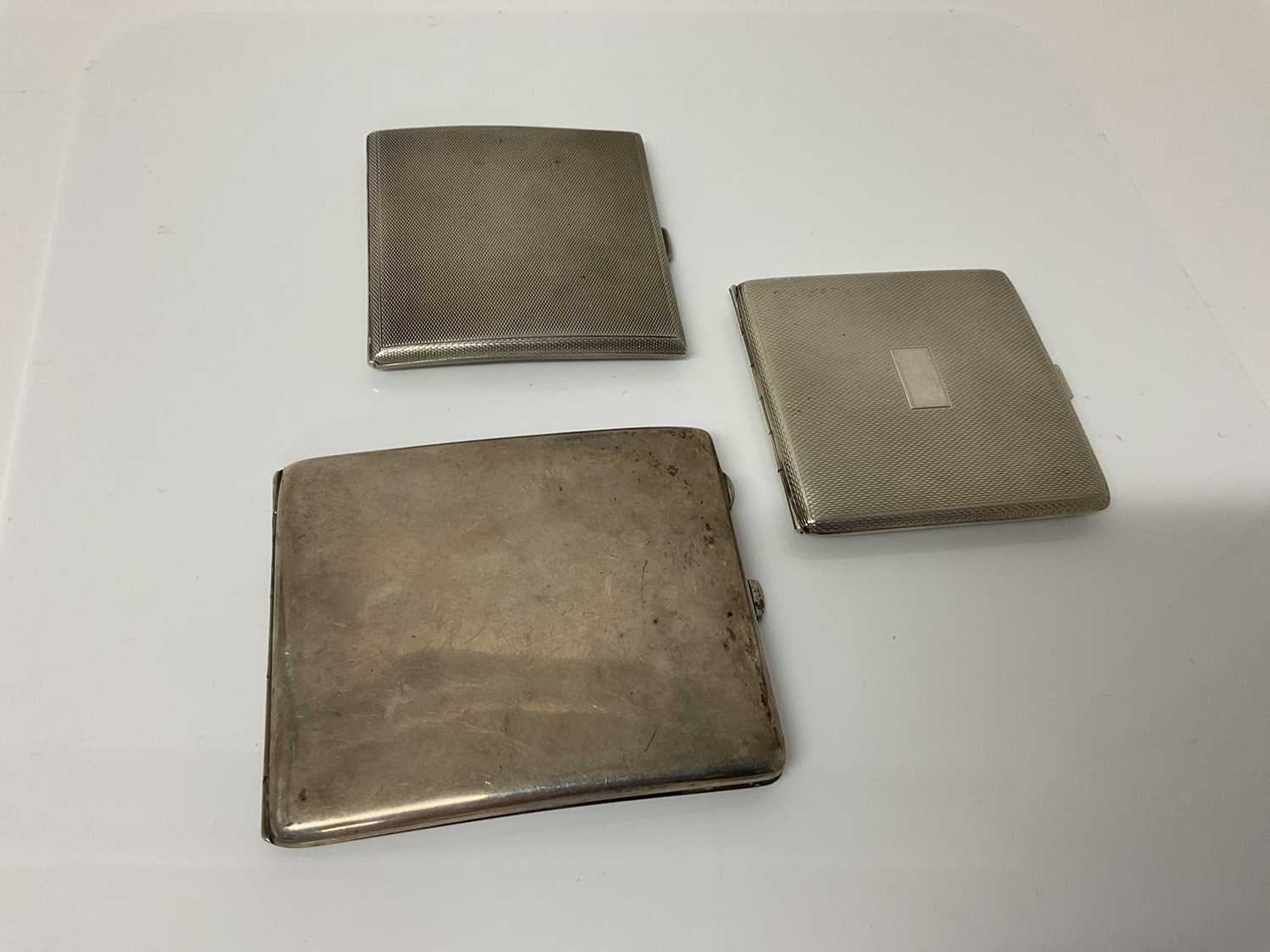 Lot 33 - George V silver cigarette case of rectangular form with engine turned decoration, (Birmingham 1922), maker William Neale Ltd, 8cmm in overall length, together with another similar white metal silve...