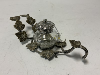 Lot 114 - Georgian silver topped cut glass inkwell, (London 1806) on a silver plated stand in the form of vine leaves, 19.5cm in length.