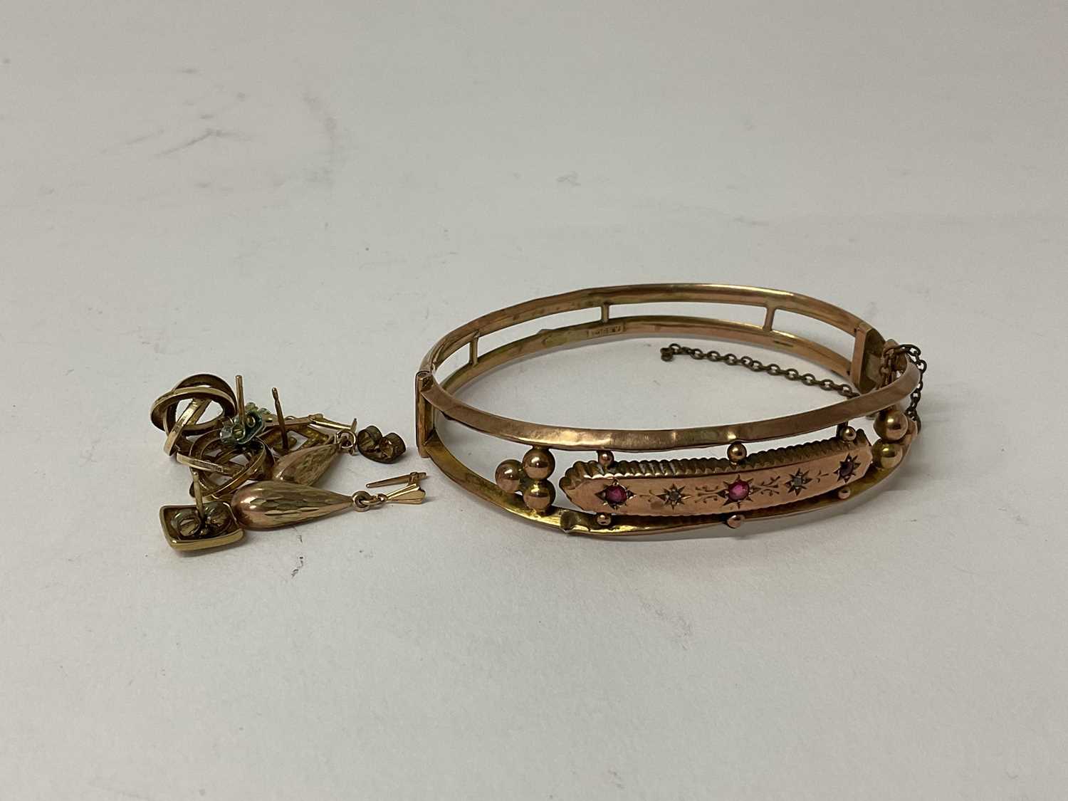Lot 79 - Edwardian 9ct gold bangle set with three coloured gem stones, together with a group of yellow metal earrings.