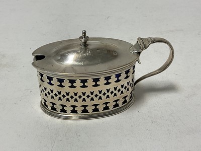 Lot 1039 - Edwardian silver mustard pot of oval form, with pierced decoration and blue glass liner, (London 1906), 9.5cm in length.