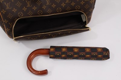 Lot 2090 - Louis Vuitton travel bag with signature monogrammed design and leather handles, together with a Louis Vuitton padlock and key, and. Versace umbrella