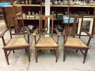 Lot 1073 - Set of three Edwardian Arts and Crafts oak elbow chairs with pierced splat backs