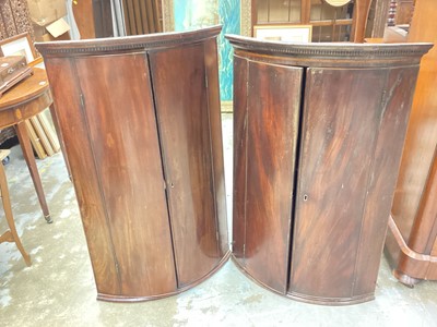 Lot 1183 - Two George III mahogany bowfront corner cupboards