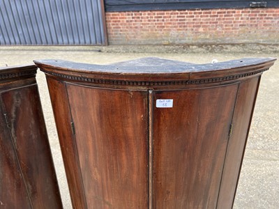 Lot 58 - Two George III mahogany bowfront corner cupboards