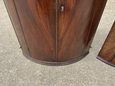 Lot 58 - Two George III mahogany bowfront corner cupboards