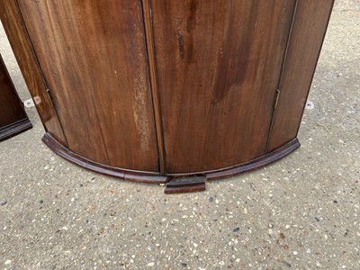 Lot 58 - Two George III mahogany bowfront corner cupboards