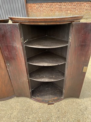 Lot 58 - Two George III mahogany bowfront corner cupboards